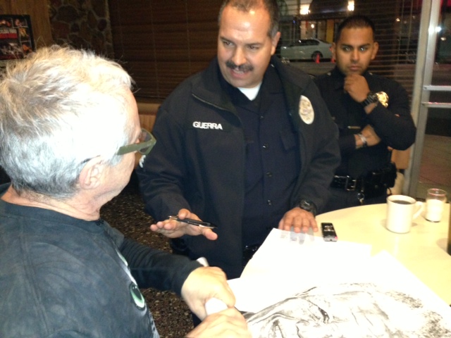 LAPD Sgt. Juan Guerra talks to guerrilla street poster artist Robbie Conal, who gave him some of his Nelson Mandela posters. (credit: Claudia Peschiutta/KNX1070)