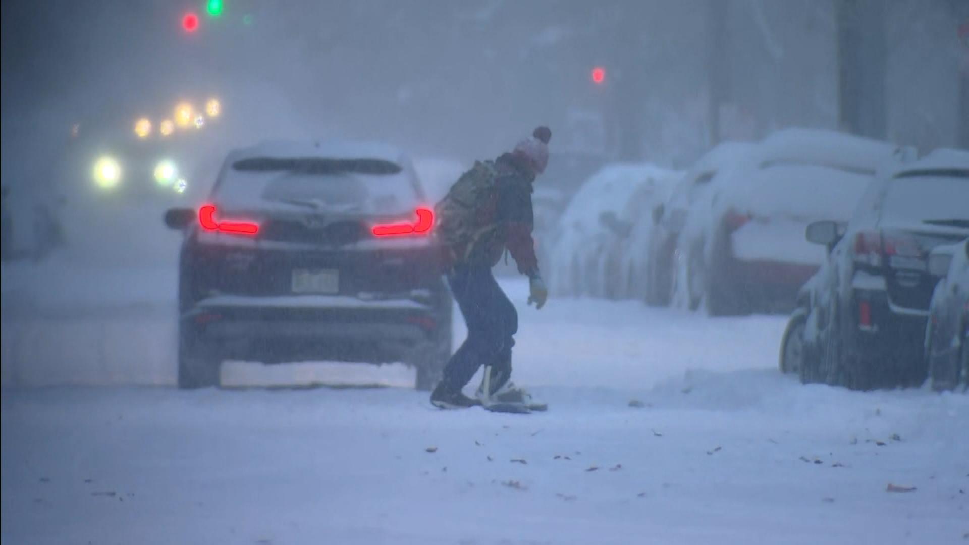 A person tries to ride a snowboard down the road in Denver Wednesday morning.