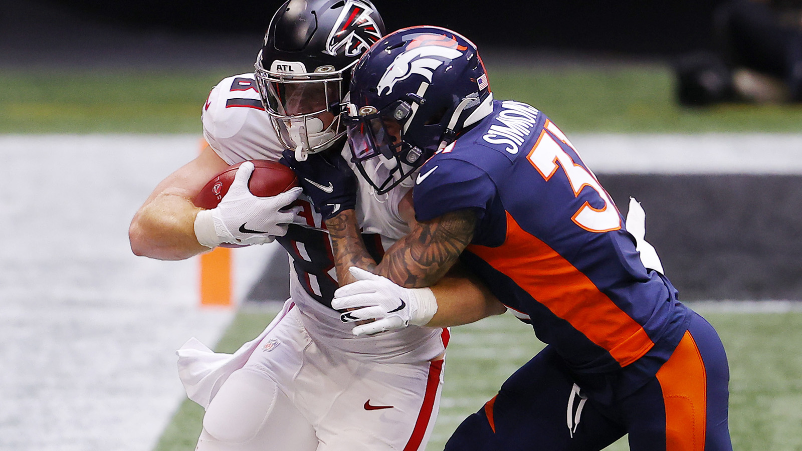 Justin Simmons #31 of the Denver Broncos tries to handle Hayden Hurst #81 of the Atlanta Falcons during the first half at Mercedes-Benz Stadium on November 8, 2020 in Atlanta.