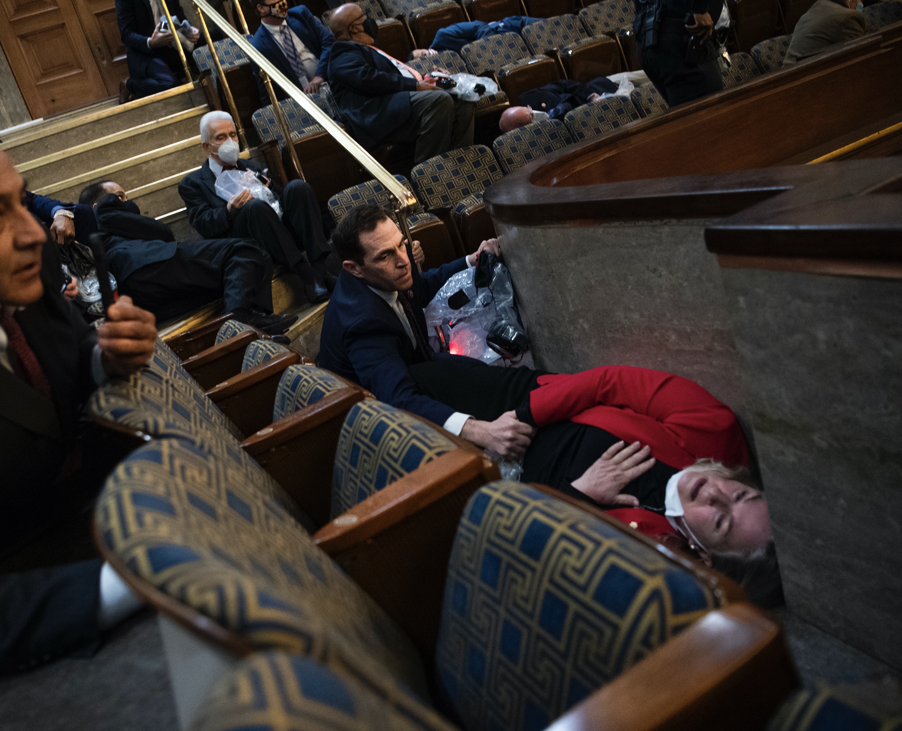 Rep. Jason Crow comforts Rep. Susan Wild while taking cover as protesters disrupt the joint session of Congress to certify the Electoral College vote on Jan. 6, 2021.