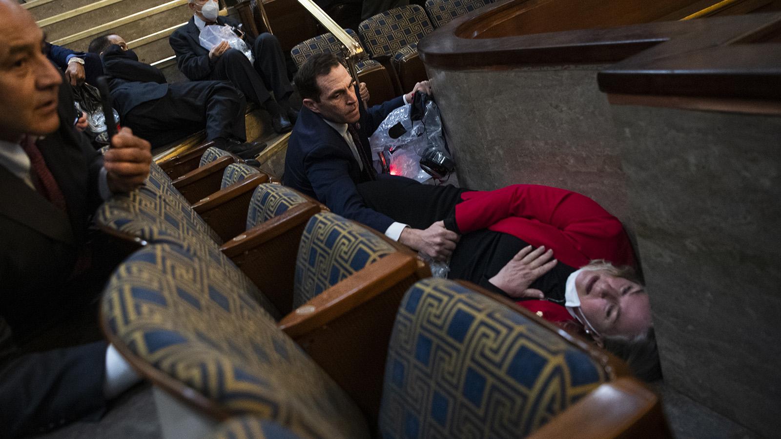 Rep. Jason Crow comforts Rep. Susan Wild while taking cover as protesters disrupt the joint session of Congress to certify the Electoral College vote on Jan. 6, 2021.