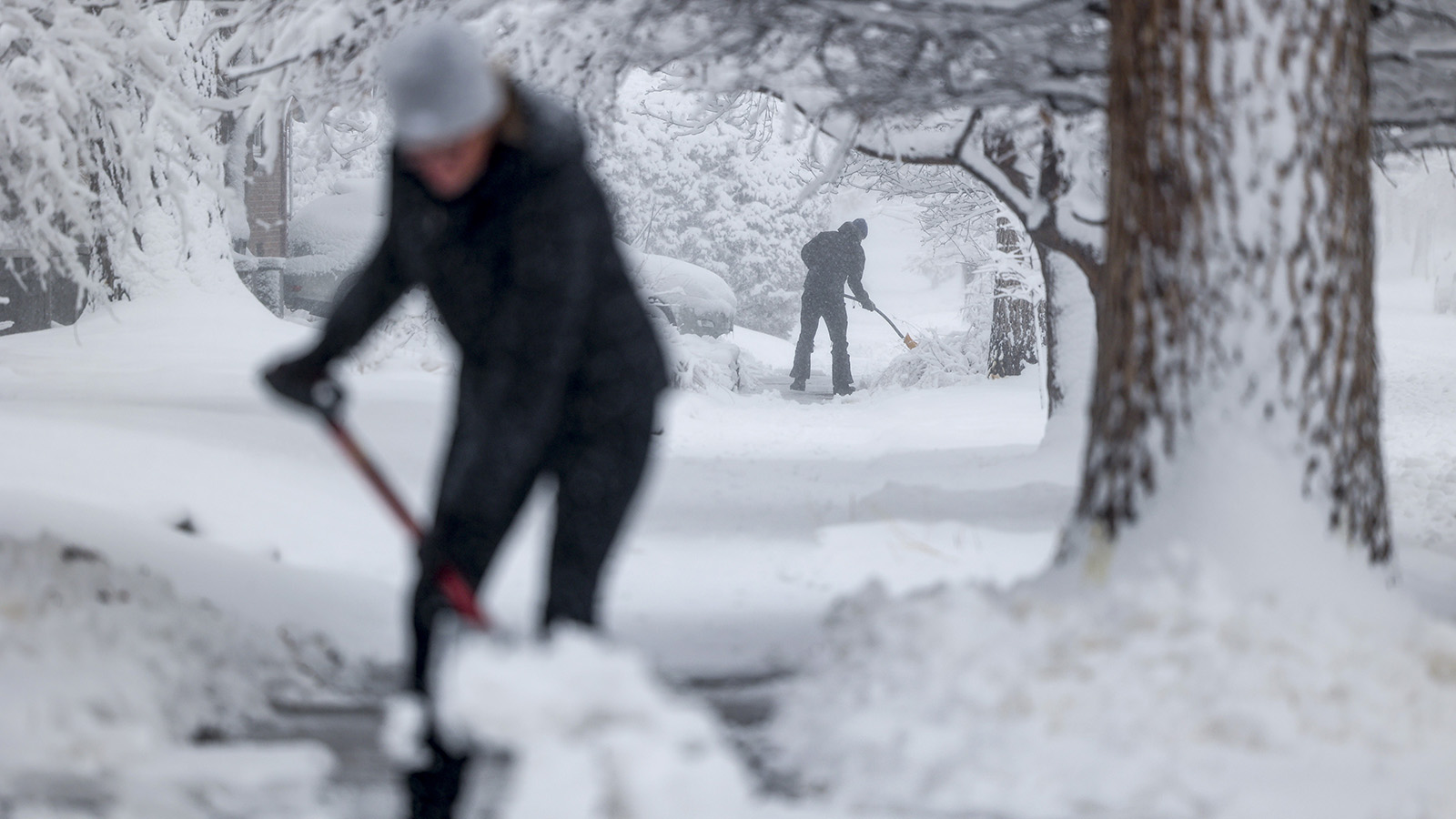 People shovel their sidewalks on March 14, 2021 in Denver, Colorado. More than 1800 flights into and out of Denver have been canceled this weekend and highways around the state have been closed down as a winter storm hits the state.