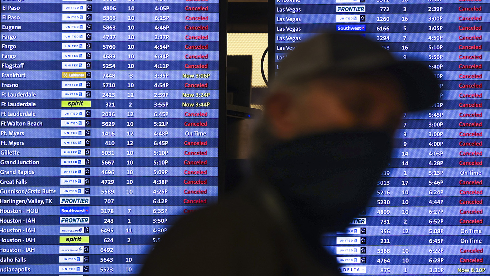 A man walks past a display board showing mostly canceled flights at Denver International Airport on March 13, 2021. 