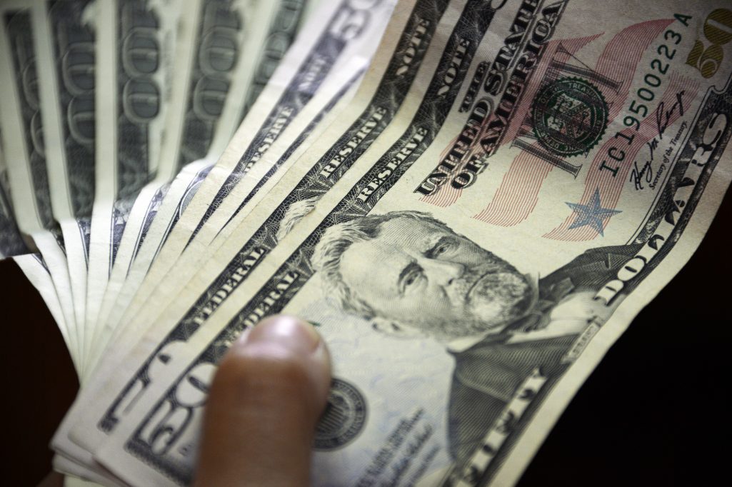 File photo of a person holding money. (Photo by JUAN BARRETO/AFP/Getty Images)