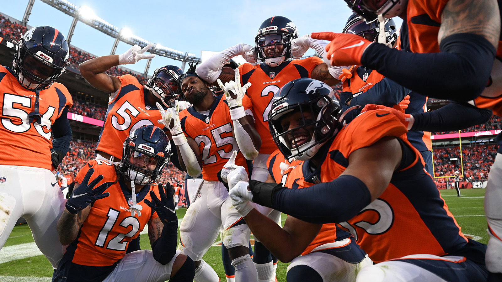 Players celebrate an interception by Denver Broncos cornerback Pat Surtain II, fifth from left, at Empower Field at Mile High on November 28, 2021.