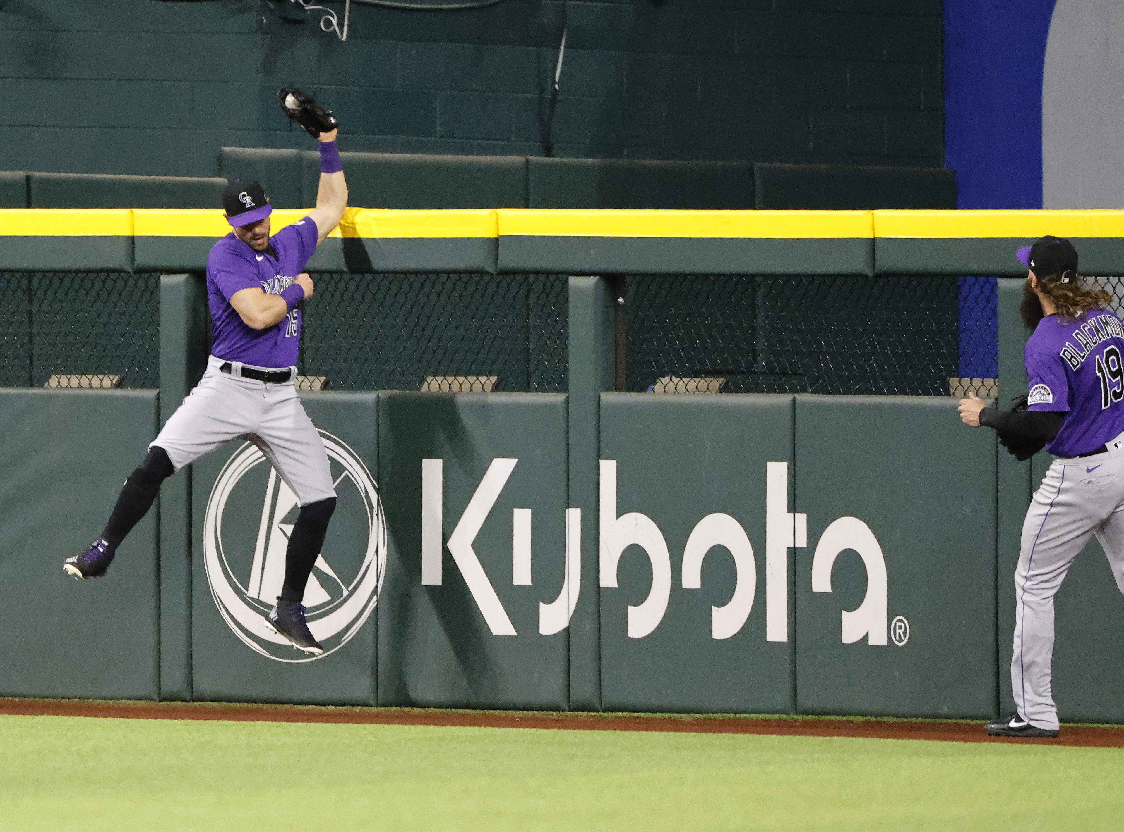 Randal Grichuk of the Colorado Rockies makes a leaping catch above the centerfield wall for a deep ball off the bat of Corey Seager of the Texas Rangers to end the fifth inning at Globe Life Field on April 12, 2022 in Arlington, Texas.