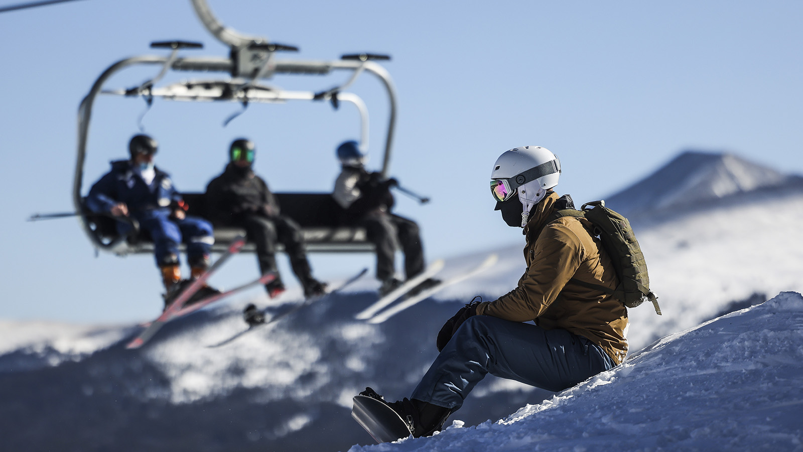 A man waits to snowboard down the mountain on opening day at Breckenridge Ski Resort on November 13, 2020.